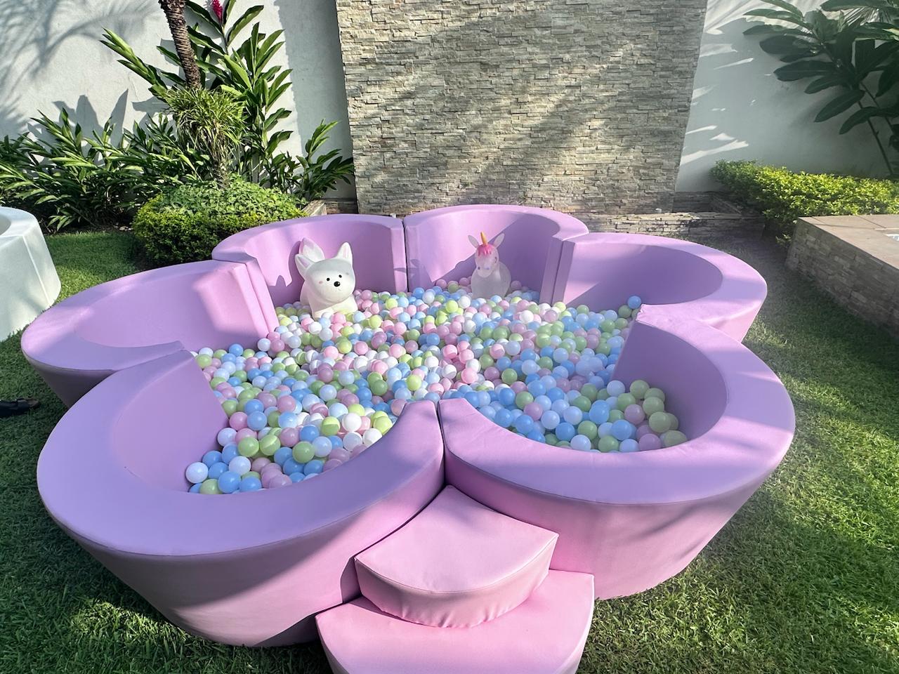 Exclusiva piscina de pelotas en forma de flor lila con juguetes de unicornio.
